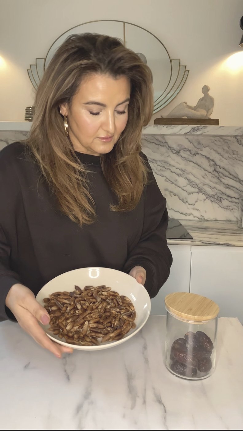 a bowl of roasted date seeds beside a jar of dates