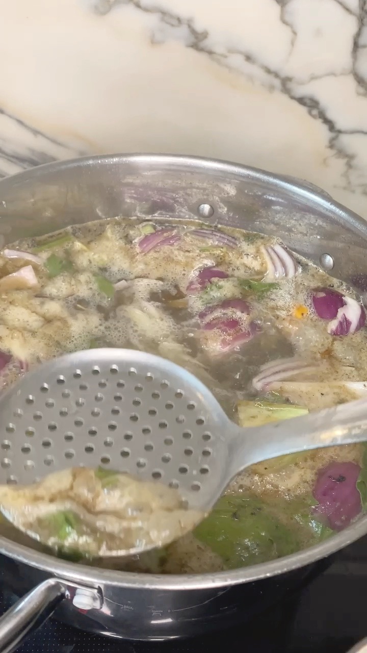 skimming the grey foam off the top with a slotted spoon