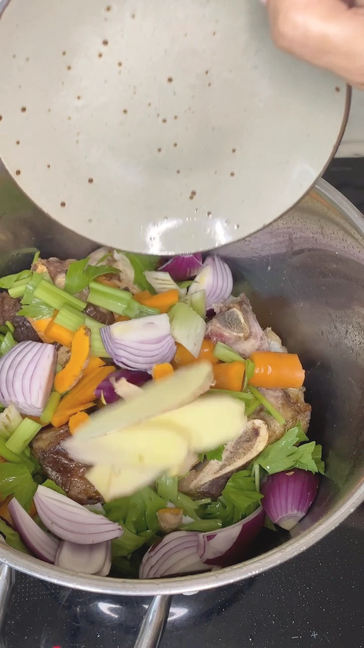 red onion, carrot, celery, parsley, garlic, ginger and fresh turmeric on top of the browned bones